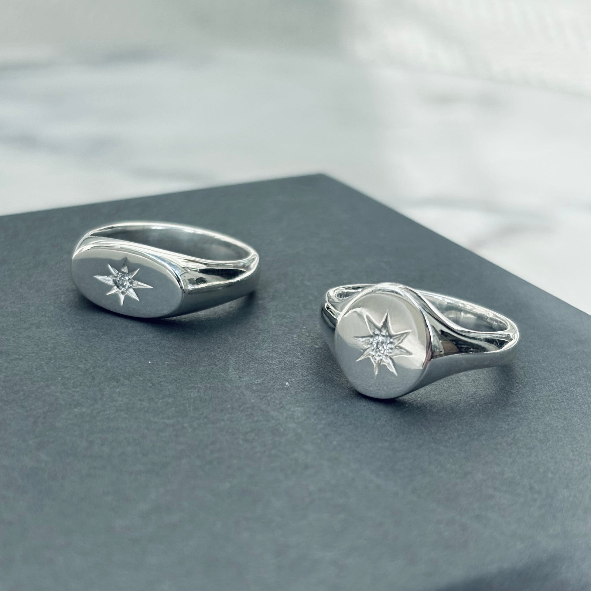 Two silver rings with star designs on a gray surface