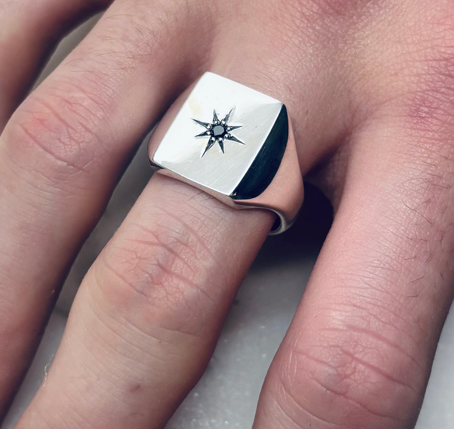 Silver large rectangular  signet ring with star set diamond on a finger