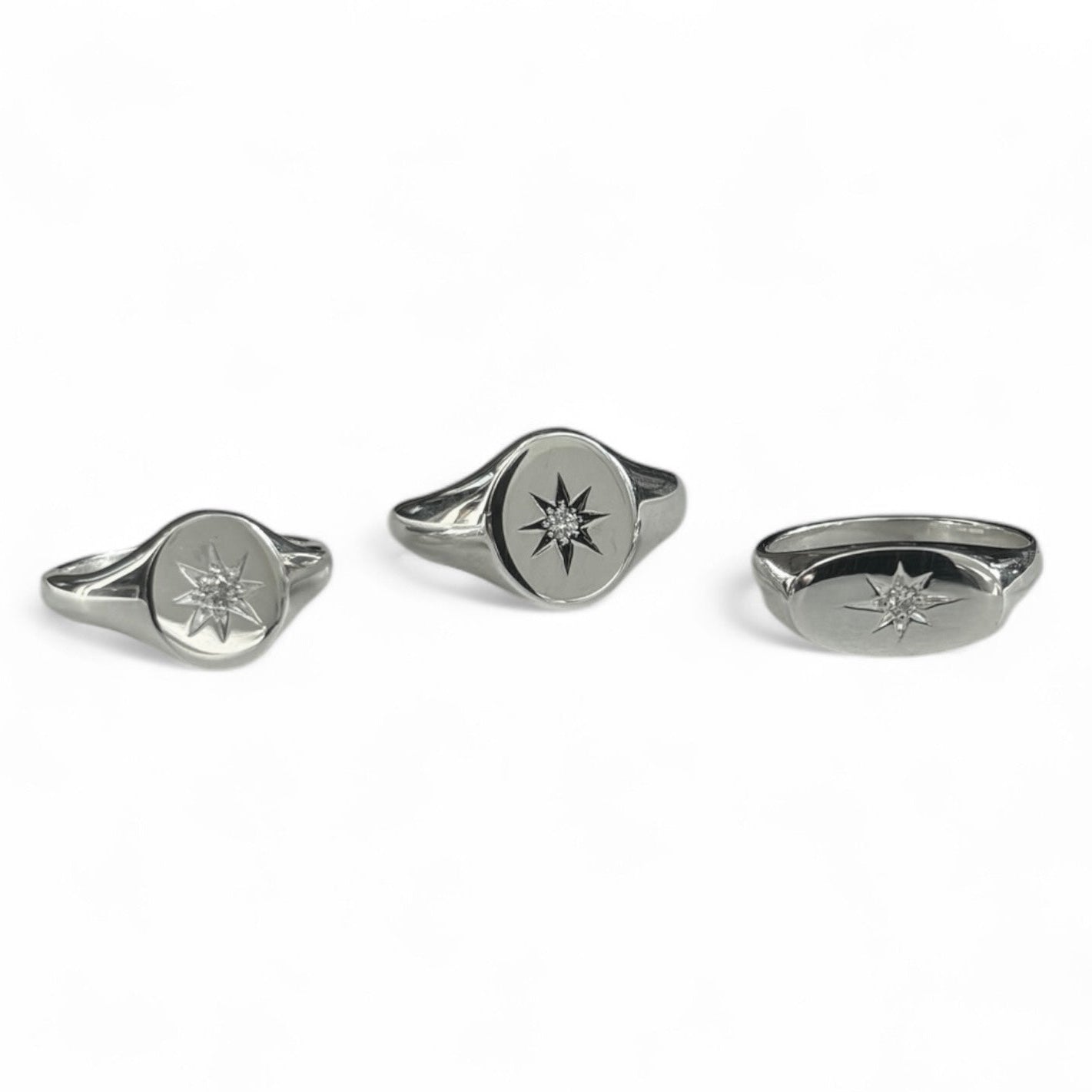 Three silver signet rings with star set diamonds on a white background