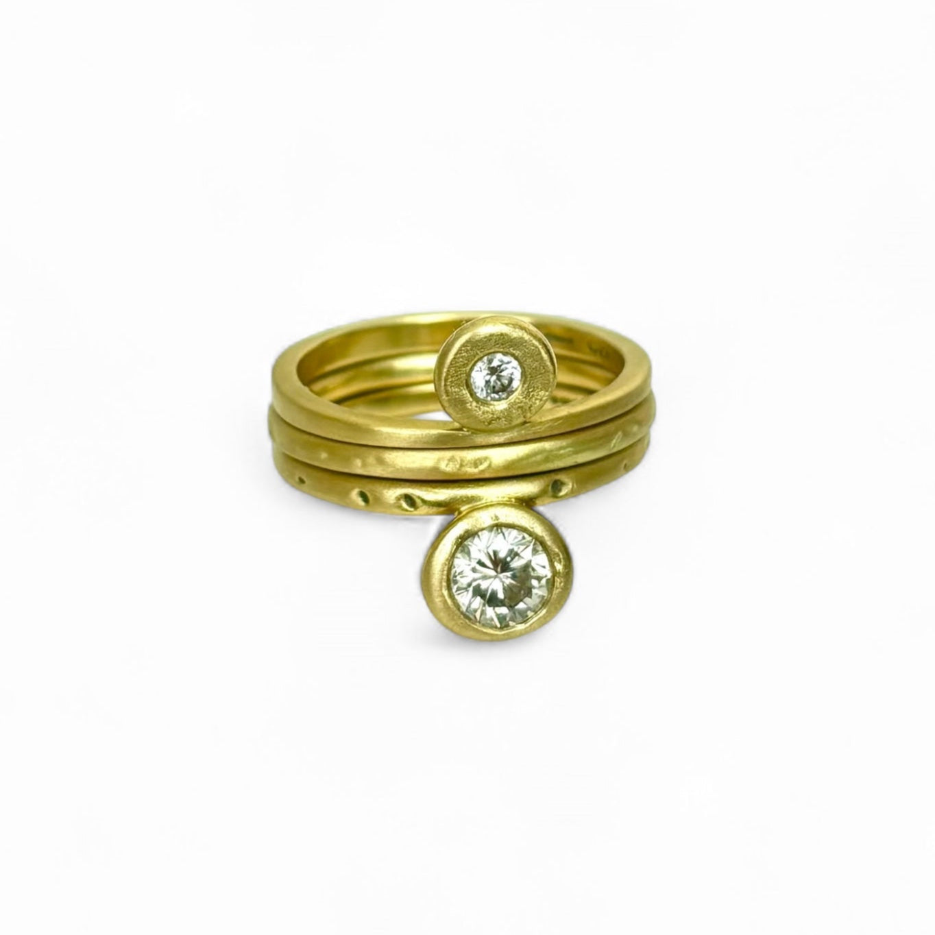 Three gold molten rings with embedded diamonds on a white background